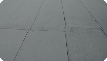 Close-up view of a flat, neatly installed roof with gray, rectangular panels.